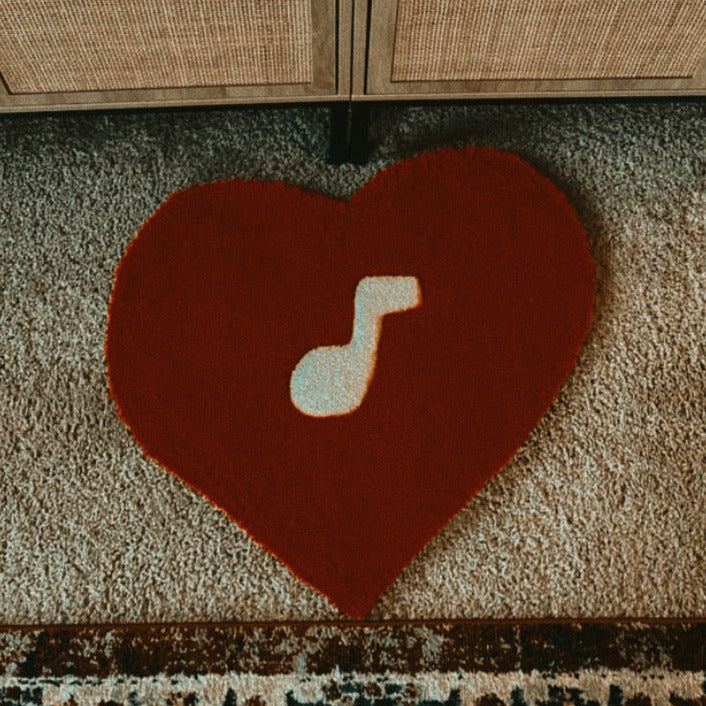 Red heart-shaped tufted rug measuring 21 inches by 21 inches, crafted from 100% acrylic yarn, featuring a white music note design at the center.